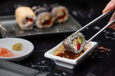 Japon yemeklerini yiyen çubuklarla ellerini yaklaştır. Geleneksel Asya dürümleri. Sebzeli ve ton balıklı Maki suşi.