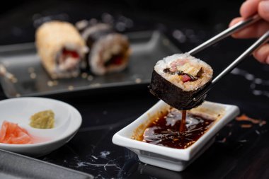 Japon yemeklerini yiyen çubuklarla ellerini yaklaştır. Geleneksel Asya dürümleri. Sebzeli ve ton balıklı Maki suşi.