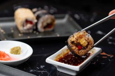 Japon yemeklerini yiyen çubuklarla ellerini yaklaştır. Geleneksel Asya dürümleri. Sebzeli ve ton balıklı Maki suşi.