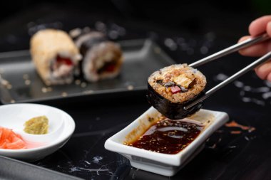 Japon yemeklerini yiyen çubuklarla ellerini yaklaştır. Geleneksel Asya dürümleri. Sebzeli ve ton balıklı Maki suşi.