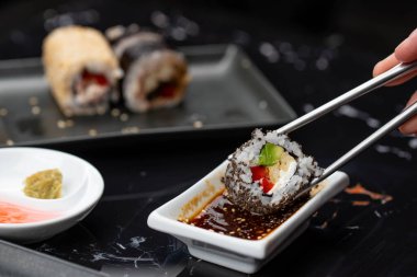 Japon yemeklerini yiyen çubuklarla ellerini yaklaştır. Geleneksel Asya dürümleri. Sebzeli ve ton balıklı Maki suşi.