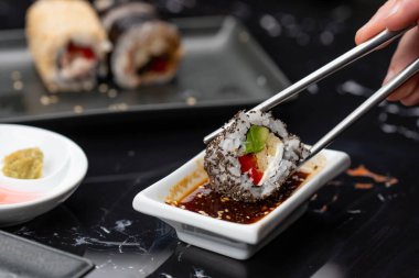 Japon yemeklerini yiyen çubuklarla ellerini yaklaştır. Geleneksel Asya dürümleri. Sebzeli ve ton balıklı Maki suşi.