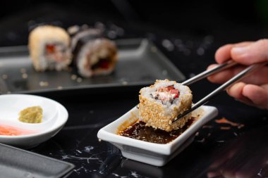 Japon yemeklerini yiyen çubuklarla ellerini yaklaştır. Geleneksel Asya dürümleri. Sebzeli ve ton balıklı Maki suşi.