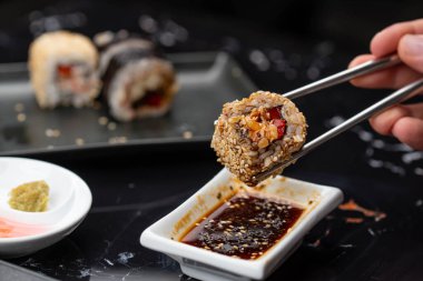 Japon yemeklerini yiyen çubuklarla ellerini yaklaştır. Geleneksel Asya dürümleri. Sebzeli ve ton balıklı Maki suşi.