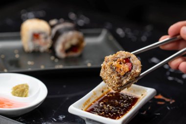 Japon yemeklerini yiyen çubuklarla ellerini yaklaştır. Geleneksel Asya dürümleri. Sebzeli ve ton balıklı Maki suşi.