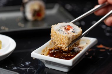 Japon yemeklerini yiyen çubuklarla ellerini yaklaştır. Geleneksel Asya dürümleri. Sebzeli ve ton balıklı Maki suşi.