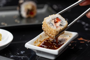 Japon yemeklerini yiyen çubuklarla ellerini yaklaştır. Geleneksel Asya dürümleri. Sebzeli ve ton balıklı Maki suşi.