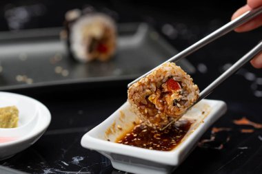 Japon yemeklerini yiyen çubuklarla ellerini yaklaştır. Geleneksel Asya dürümleri. Sebzeli ve ton balıklı Maki suşi.