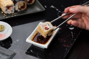 Japon yemeklerini yiyen çubuklarla ellerini yaklaştır. Geleneksel Asya dürümleri. Sebzeli ve ton balıklı Maki suşi.