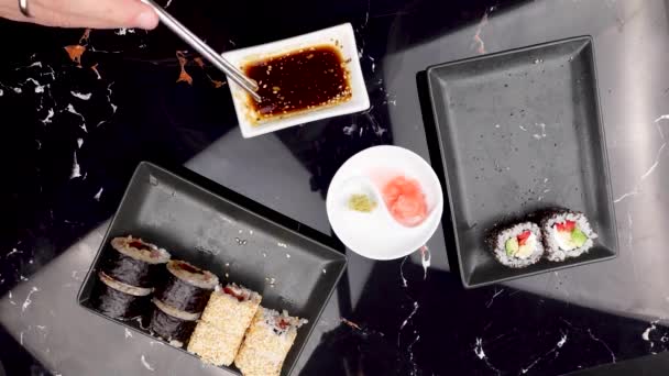 用筷子把吃日本菜的人的手拉近 传统的亚洲卷 马基寿司加蔬菜和金枪鱼Wasabi和Soy Sauce在碗里 — 图库视频影像