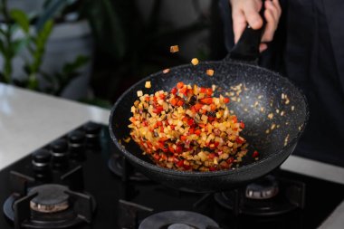 Şef 'in ellerini yakın pişirin ve fırında soğan, biber, şitake mantarı, lahana, tavada sarımsak pişirin. Uçan yiyecek havalanması.
