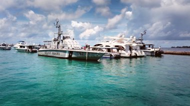 Erkek Sahil Güvenlik ve diğer derin deniz tekneleri, yatlar ve gemiler muhteşem mavi gökyüzü ve beyaz kabarık bulutlarla adanın limanına yanaştı.