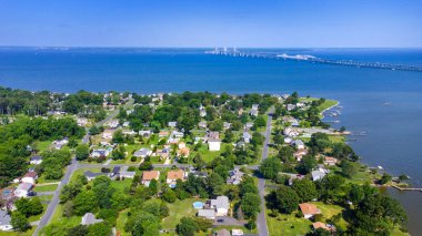 Maryland 'in doğu kıyısında Chesapeake Körfezi Köprüsü' nün arka planında bulunan evlerin insansız hava aracı fotoğrafı.