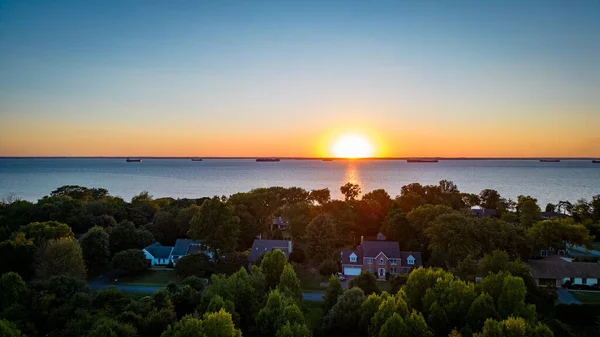 Maryland Chesapeake Körfezi 'nde gün batımının insansız hava aracı fotoğrafı. Gemiler geçiyor ve evler ön planda.