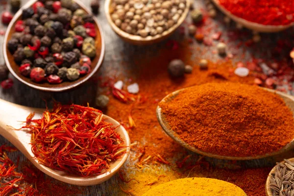 Arka planda kaşıkta çeşitli baharatlar var. Mutfak masasında yemek pişirme konsepti ve malzemeleri yakın plan.