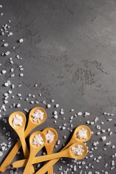 用勺子把水晶海盐撒在混凝土石桌的背景上 厨房桌顶部的食物配料 图库图片