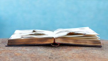 Paslı metal bir yüzey üzerine açık yanmış bir kitap.