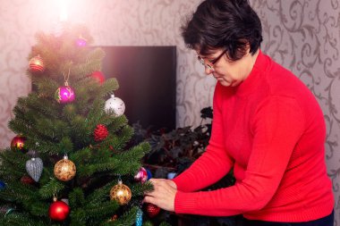 A woman decorates a Christmas and New Year tree. Preparation for Christmas and New Year