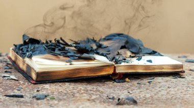 İçinde yanmış sayfalar ve kitabın üstünde duman olan açık bir kitap. Yangından sonraki kitap.