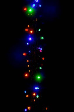 Christmas and New Year garland with bright multi-colored lights on black isolated background, copy space