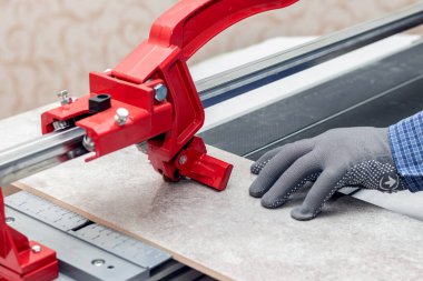 A worker cuts facing tiles with a tile cutter