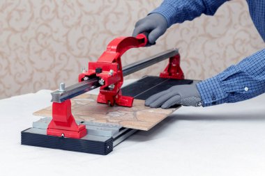 A worker cuts facing tiles with a tile cutter