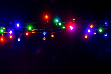 Christmas and New Year garland with bright multi-colored lights on black isolated background, copy space