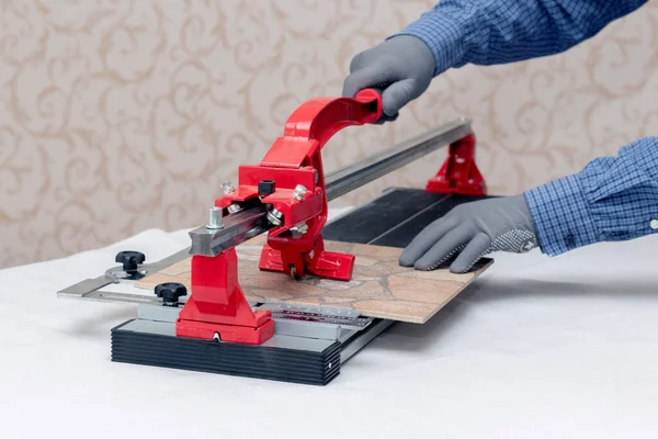 Stock image A worker cuts facing tiles with a tile cutter