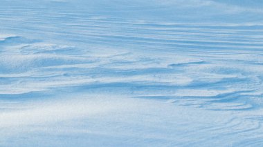 Snowy background, snow-covered surface of the earth after a blizzard in the morning in the sunlight with distinct layers of snow