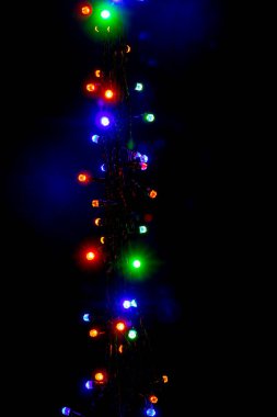 Christmas and New Year garland with bright multi-colored lights on black isolated background, copy space