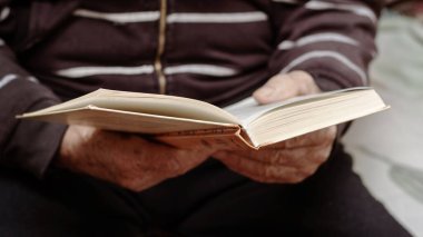 Yaşlı bir adam, bir dede, elinde açık bir kitap tutuyor. Yaşlılar için boş zaman. Kitap okuyorum.