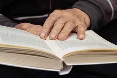 Yaşlı bir adam, bir dede, elinde açık bir kitap tutuyor. Yaşlılar için boş zaman. Kitap okuyorum.