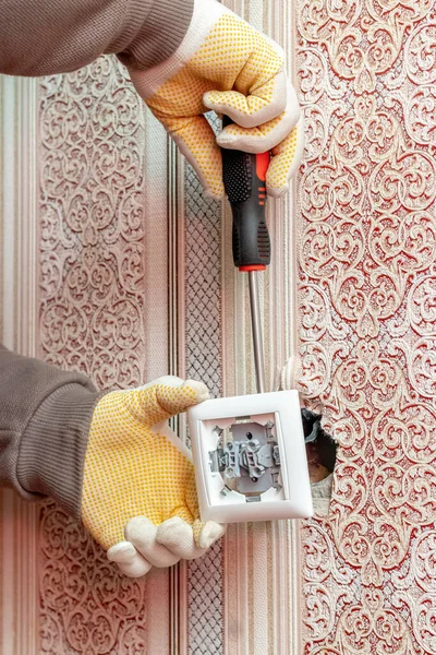 An electrician installs a switch in a private house
