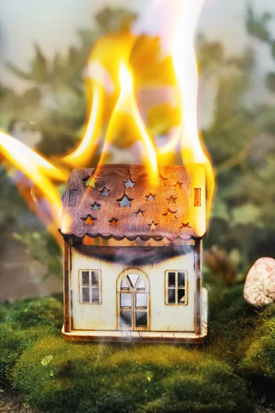 A toy wooden house is burning in nature. Fire concept. Fire safety