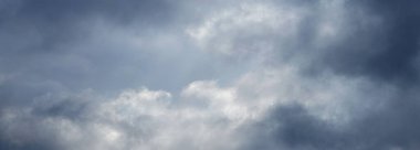 Gri bulutlu gök gürültülü gök gürültülü, güneş ışığı kara bulutların arasından zar zor geçiyor.