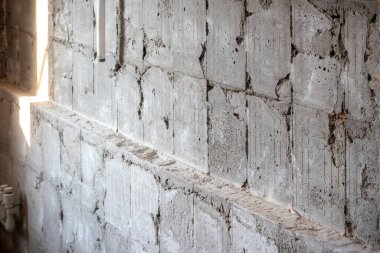 Paramparça olmuş gri beton bir duvarın dokusu. Yüzü kiremitlere bakıyor ve bir şerit ışığa bakıyor.