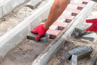 Bir işçi parktaki merdivenlere asfalt döşeyerek uzanır.