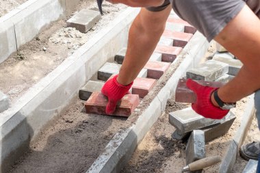 Bir işçi parktaki merdivenlere asfalt döşeyerek uzanır.