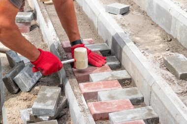 Bir işçi parktaki merdivenlere asfalt döşeyerek uzanır.