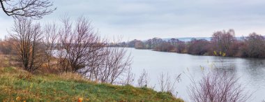 Nehir kıyısında çıplak ağaçlarla sonbahar manzarası