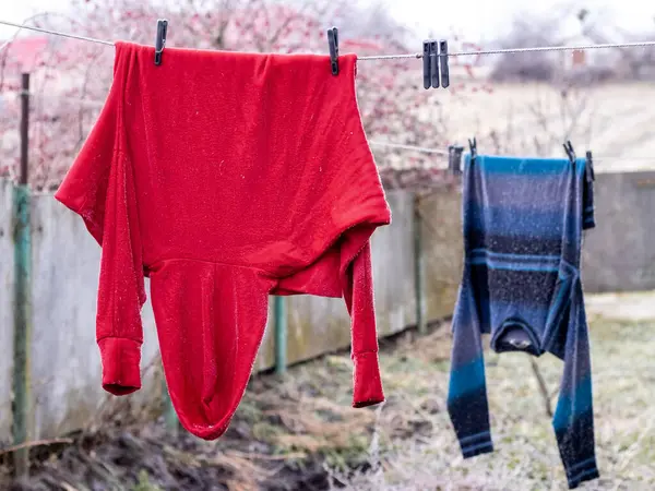 Clothes, sweaters are hanging on a clothesline to dry in the backyard. Drying clothes