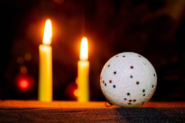 Bir Noel ağacı topu ve bir Noel ağacının arka planında yanan mumlar.