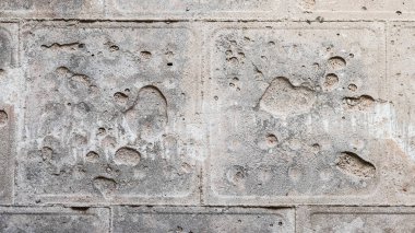 Paramparça olmuş gri beton duvarın dokusu fayanslara bakıyor.
