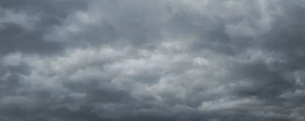 The dark stormy sky is covered with dense gray clouds