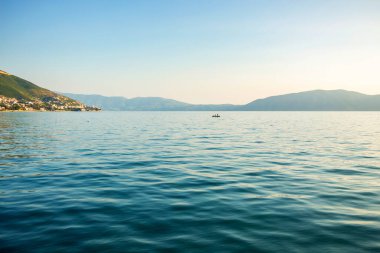 Mavi gökyüzünün arka planında kayalık bir kıyı olan deniz. 