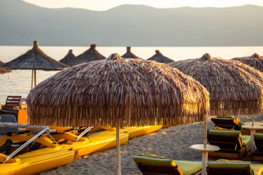 Sahilde şemsiyeli ve güneşli yataklı bir sahil.