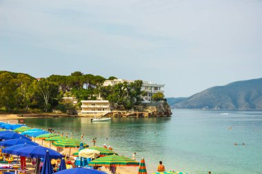 Kayalık bir sahilde turistler için şemsiyeli ve daireli deniz plajı