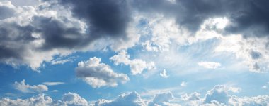 Katmanlı yağmur bulutları güneşli gökyüzünde asılı.