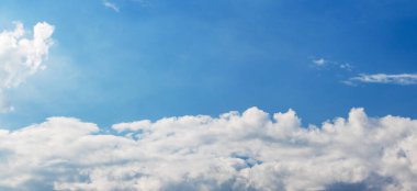  Çerçevenin altında beyaz kümülüs bulutları ve üstünde açık mavi bir gökyüzü var.