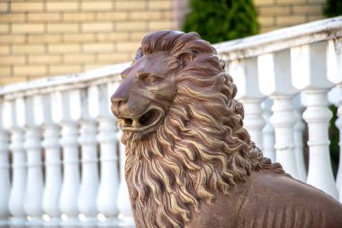 Beyaz balyaların yanında duran kendine özgü yelesi olan bir aslan heykelinin yakın çekimi.